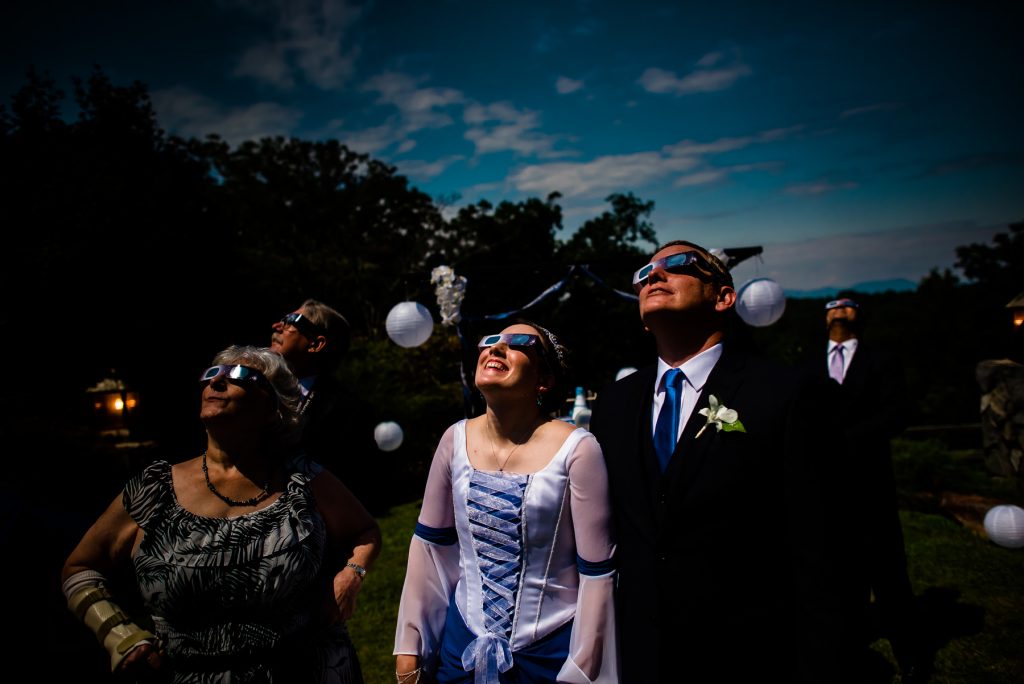 bride and groom watching eclipse with glasses during wedding